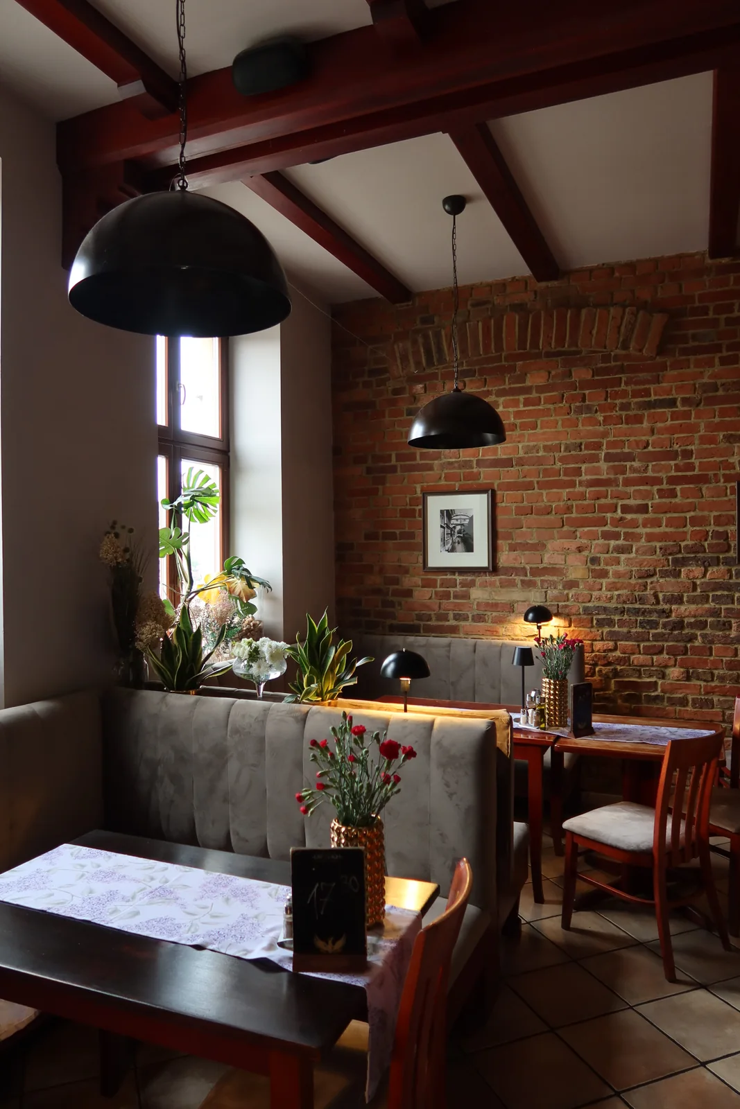 Stoliki z szarymi kanapami, ceglaną ścianą i ciepłym światłem w restauracji Sorrento