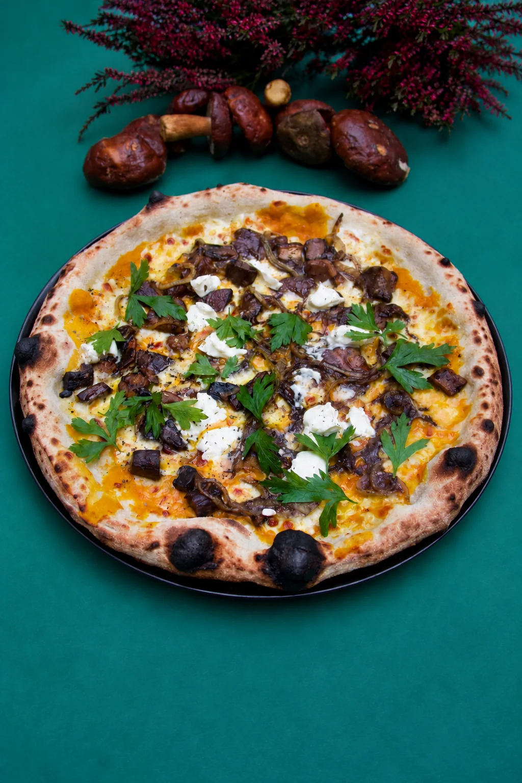 Pizza grzybowa z natką pietruszki na ciemnym talerzu
