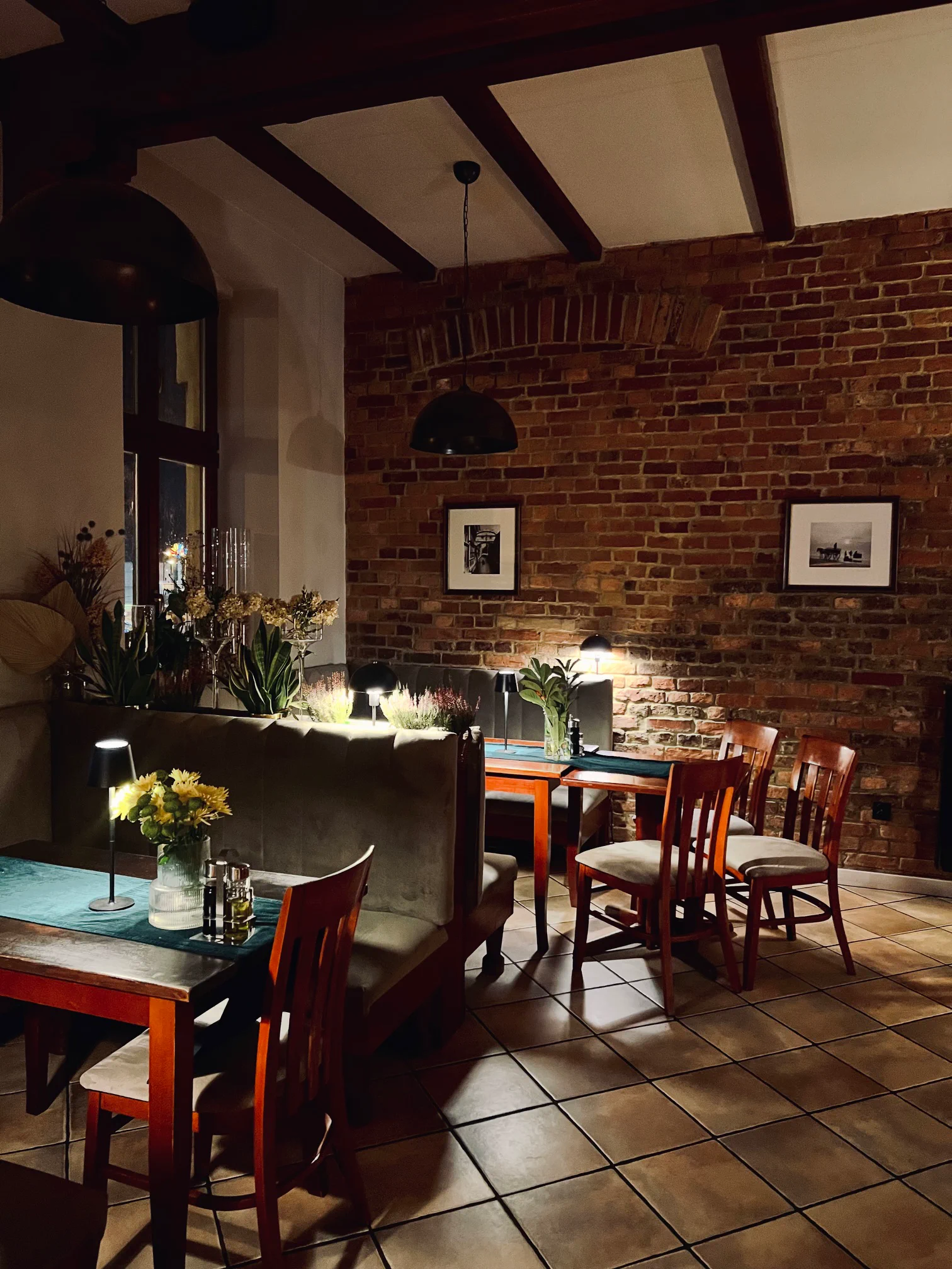 Stoliki w ceglanym wnętrzu restauracji Sorrento, oświetlone lampkami wieczorem